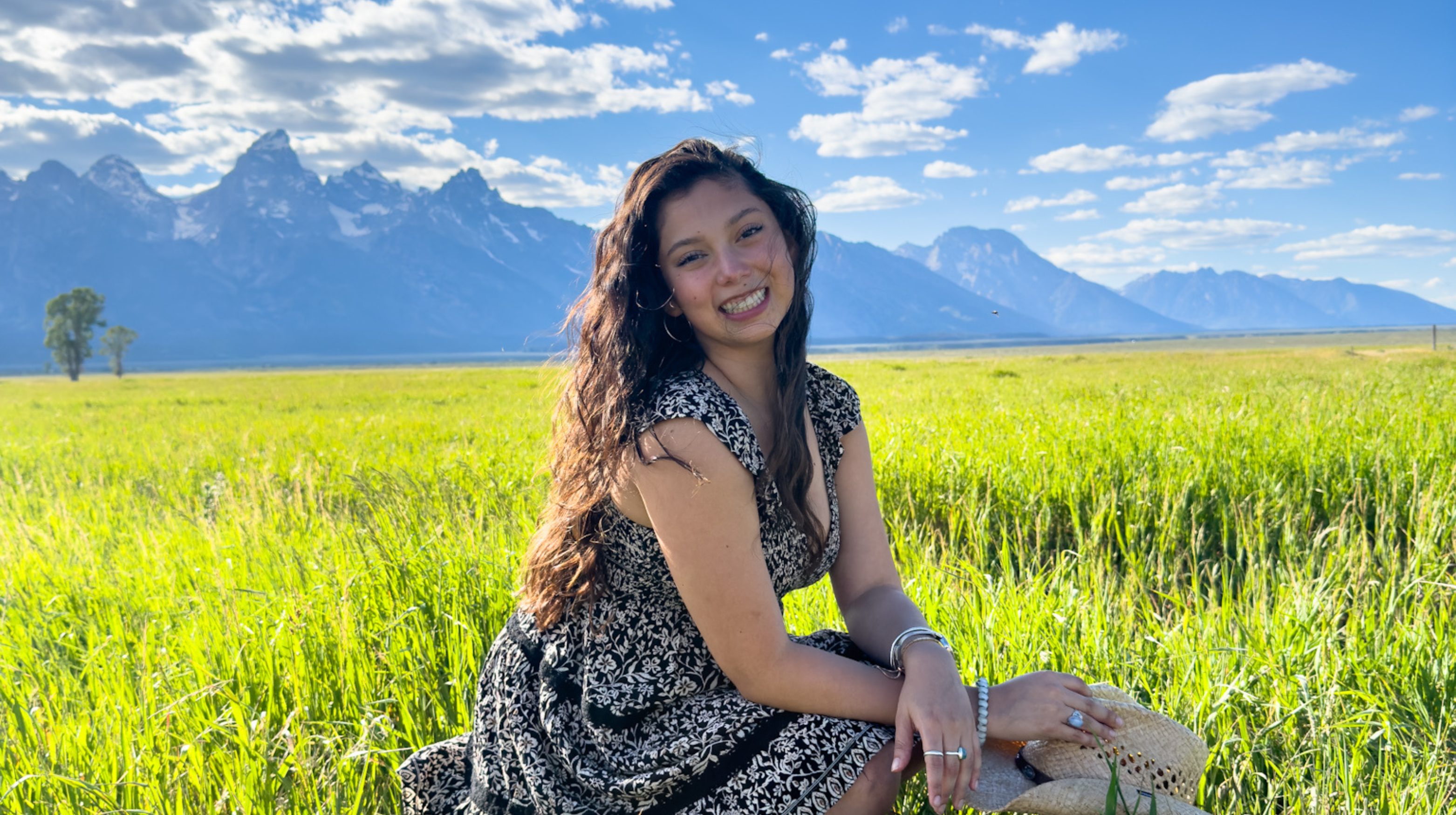 A girl sitting in the grass in front of the mountains